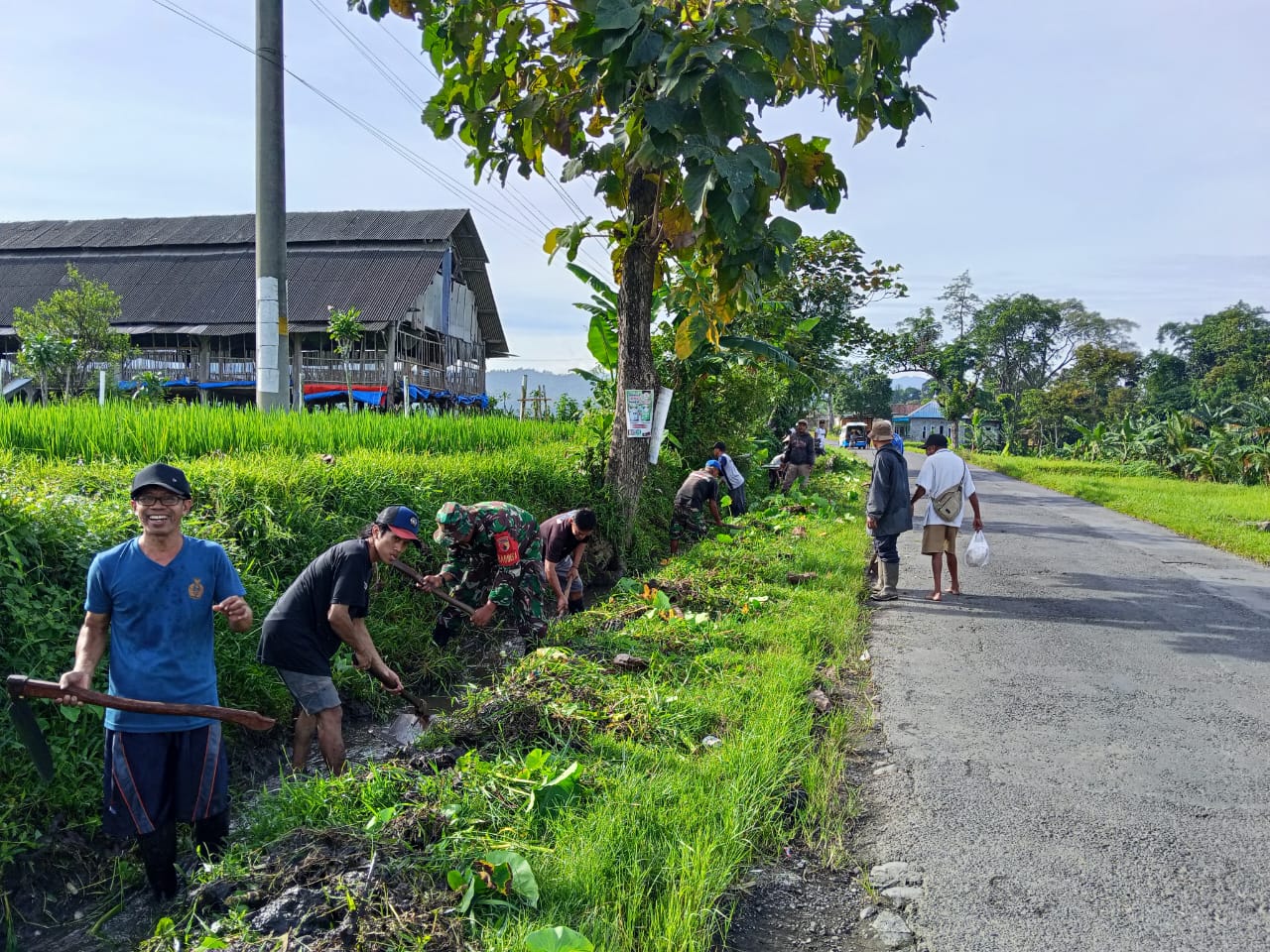 Tangan-tangan warga yang memegang alat tradisional seperti cangkul dan sabit, simbol dari gotong royong yang telah menjadi budaya turun-temurun bangsa Indonesia dalam mengatasi masalah bersama.